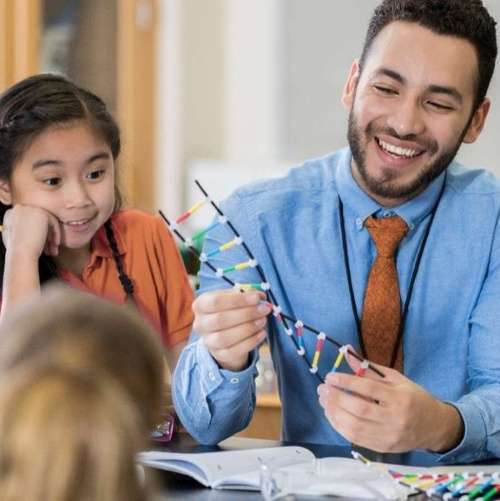 Male teacher showing DNA strand to student.